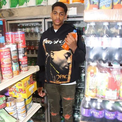 He is holding an orange juice and wearing a shirt with 2pac on it.